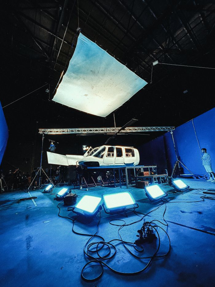 A helicopter fuselage on a film set with chroma key background and bright lighting.
