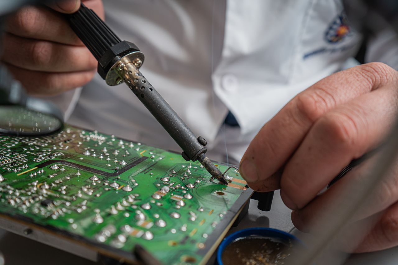 Mastering the First Impression: Your intriguing post title goes here Technician performing precise soldering on a circuit board for electronics repair.